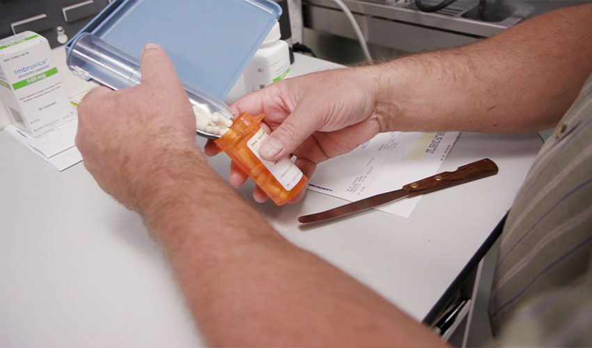 a pharmacy technician putting oral chemotherapu pills in a bottle