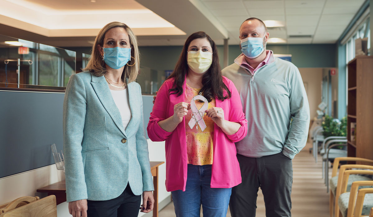 NCODA member, cancer care specialist Dr. Eleni Nackos, stands with a patient who is holding a pink cancer ribbon