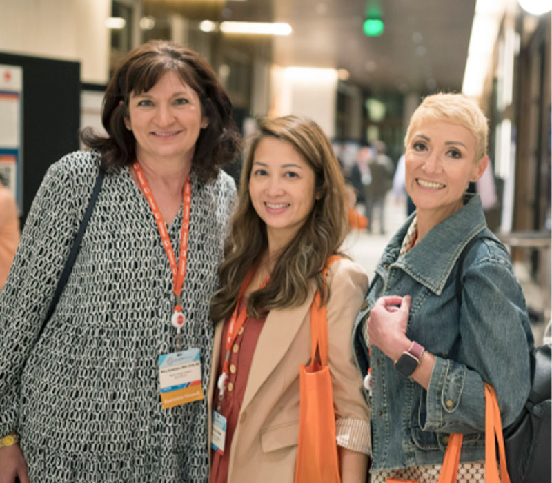 Three NCODA members at the fall summit stand together and smile into the camera